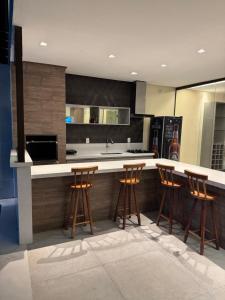 eine Küche mit einer Theke mit vier Barhockern in der Unterkunft Sanzecasadapraia in São José da Coroa Grande