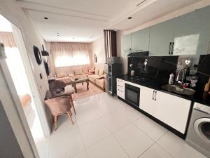 a kitchen with a sink and a living room at Le Style in Mehdiya-Plage