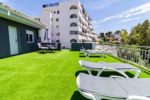 a balcony with green grass and white chairs at Villa Amir in Fuengirola