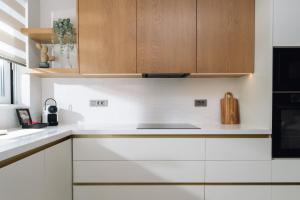 a kitchen with white counters and wooden cabinets at Nuvélia, A Minimalist Luxury Story in Zakynthos Town +7 photos