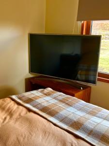 TV de pantalla plana en una habitación con cama en Confortable cabaña de campo, en Coyhaique