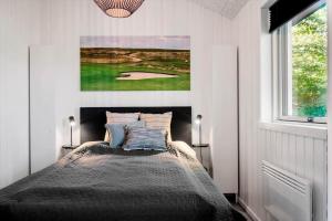 Un dormitorio con una cama y una imagen de un campo de golf. en LF11106-Struer-Slugten-6, en Humlum
