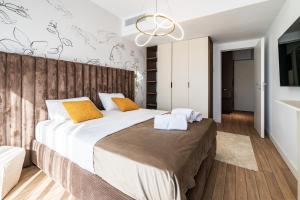 Maison Lumière - A modern Designer Apartment in Central Bucharest في بوخارست: غرفة نوم بسرير كبير مع شراشف بيضاء ومخدات برتقالية