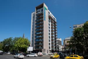 Maison Lumière - A modern Designer Apartment in Central Bucharest في بوخارست: مبنى مرتفع مع سيارات متوقفة أمامه