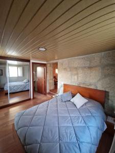 a bedroom with a large bed with a stone wall at Casa da Biquinha in Vouzela