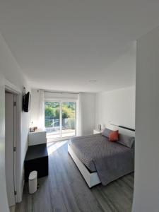 a white bedroom with a bed and a window at Casa da Biquinha in Vouzela
