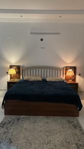 a bedroom with a large bed with two lamps on it at إستراحة البستان in Ash Shuwaybiţ