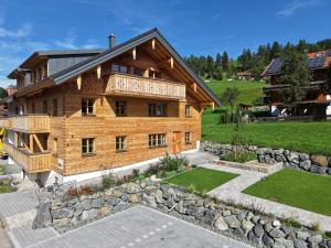 a large wooden house with a stone wall at DAS BISCHOF - 5 exklusive Ferienwohnungen mit privaten Zirbensaunen - inkl Hindelang PLUS in Bad Hindelang