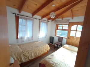 a bedroom with two beds and a chair and windows at Casa Sueño in San Martín de los Andes