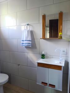 a bathroom with a sink and a toilet and a mirror at Cantinho da Isa in Pomerode +4 photos