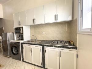 a kitchen with white cabinets and a stove top oven at Tamraght Waves Retreat in Tamraght Ouzdar