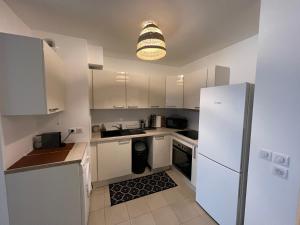 a kitchen with white cabinets and a white refrigerator at Spacious apartment in Ivry-sur-Seine