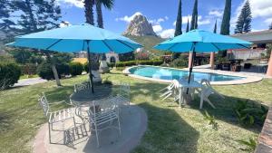 a table and chairs with umbrellas next to a pool at Hotel Quinta Mirador Zacualli in Bernal