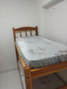 a small wooden bed in a room with a white wall at A Matriarca in Bom Jesus da Lapa