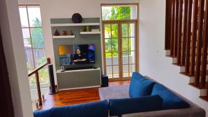 a living room with a blue couch and a tv at Samara Villa by Trillium Residencies in Nugegoda