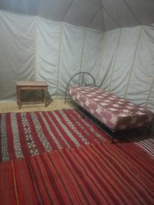 a bedroom with a bed and a table in a tent at Camp azawan hananich  +2 photos