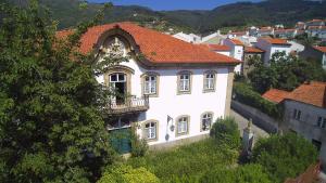 a white house with a red roof on a hill at Casa Das Obras in Manteigas