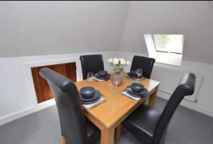 a dining room table with black chairs and a table with flowers at The Penthouse in Norwich