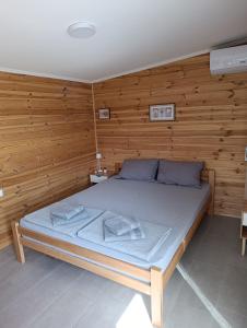 een bed in een kamer met een houten wand bij Vikendica Blagojević Čačak in Čačak