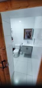 a white bathroom with a toilet and a sink at Refugio Cesaria in Tarrafal