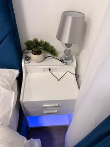 a nightstand with a lamp and a plant on it at Modern En-Suite Double Bedroom in Cardiff with Private Entrance in Cardiff