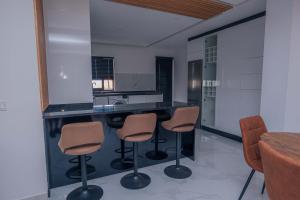 a kitchen with a counter with three stools and a mirror at Otro Residence in Praia