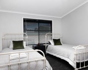 two beds in a white room with a window at The Crossing Motel in Junee