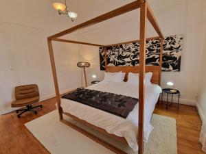 a bedroom with a canopy bed and a chair at Karoocible Cycling House in Ladismith