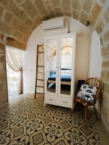 Zimmer mit einem weißen Schrank und einem Stuhl in der Unterkunft Antico Gelso in Polignano a Mare