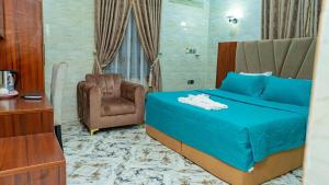 Un dormitorio con una cama azul y una silla. en Winngs Hotels and Banquet, en Uyo