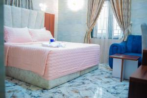 1 dormitorio con cama rosa y silla azul en Winngs Hotels and Banquet, en Uyo