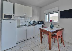 Akwaba chez Paule في نانت: مطبخ به دواليب بيضاء وطاولة عليها مزهرية +7 صور