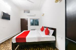 Un dormitorio con una cama con almohadas rojas. en Hotel O Kavyanjali, en Ayodhya