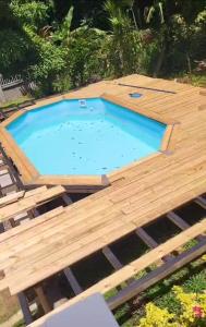 a large swimming pool with a wooden deck around it at Villa IXORA in Trois-Rivières