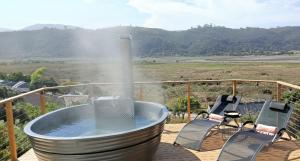 a hot tub sitting on a deck with two chairs at SuPaViews in Wilderness