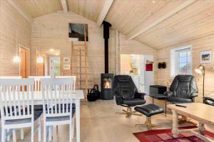 a living room with a table and chairs and a fireplace at 128-Ringkobing-Troldedalen-18 in Nørby