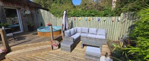 a patio with a couch and a hot tub on a wooden deck at The Wendy house in Parkend