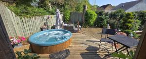 bañera de hidromasaje en una terraza de madera con sombrilla en The Wendy house, en Parkend