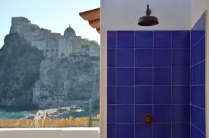 a blue tiled bathroom with a view of a mountain at Terrazza Aragonese in Ischia Town
