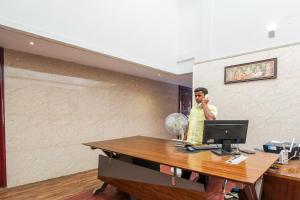 a man in an office talking on a cell phone at Super Hotel O Am Grandd in Tiruchchirāppalli +14 photos