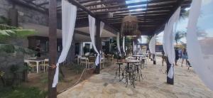 a patio with tables and chairs and white curtains at Búzios Beach Resort in Buzios