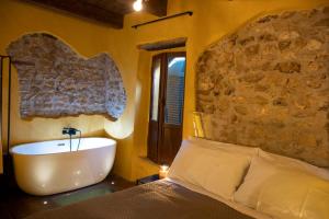 1 dormitorio con cama y bañera junto a una pared de piedra. en Rustico di charme, en Fiano Romano