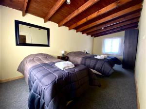 a room with two beds and a mirror in it at Casa Los Huemules in El Chalten