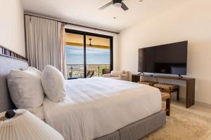 a bedroom with a large bed with a flat screen tv at Luxury Pedregal Condo - Views, Pool & Concierge in Cabo San Lucas