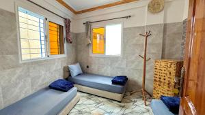 a room with two beds and two windows at Swet Surf Hostel in Taghazout