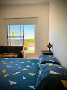 a bedroom with a bed with a blue comforter with yellow triangles at Charming flat with big private Terrace in Montevideo