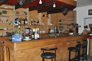 un bar con taburetes negros en un mostrador con botellas de alcohol en Le Castellou, en Conques