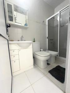 a white bathroom with a toilet and a sink at Moderna casa en barrio tranquilo in Villa Ángela