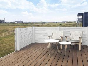 Torstedにある6 person holiday home in Thistedの柵のあるデッキにテーブルと椅子が2つある