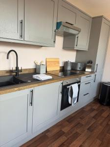 een keuken met witte kasten en een spoelbak bij Blackburn Heights Sleeps 4 Family Apartment in Bridlington